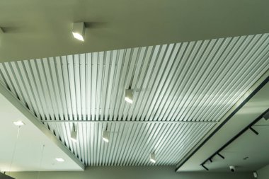 Modern bir depoda parlak ışıkları olan bir tavan, alışveriş merkezi binası, ofis veya diğer ticari gayrimenkul eşyaları. Tavanın altındaki raylarda LED ışıkları