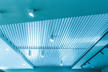 Modern bir depoda parlak ışıkları olan bir tavan, alışveriş merkezi binası, ofis veya diğer ticari gayrimenkul eşyaları. Tavanın altındaki raylarda LED ışıkları