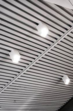 Modern bir depoda parlak ışıkları olan bir tavan, alışveriş merkezi binası, ofis veya diğer ticari gayrimenkul eşyaları. Tavanın altındaki raylarda LED ışıkları