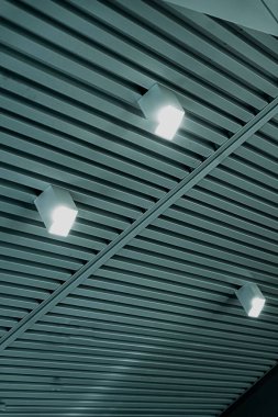 Modern bir depoda parlak ışıkları olan bir tavan, alışveriş merkezi binası, ofis veya diğer ticari gayrimenkul eşyaları. Tavanın altındaki raylarda LED ışıkları