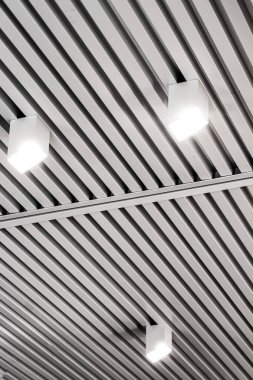 Modern bir depoda parlak ışıkları olan bir tavan, alışveriş merkezi binası, ofis veya diğer ticari gayrimenkul eşyaları. Tavanın altındaki raylarda LED ışıkları