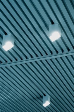 Modern bir depoda parlak ışıkları olan bir tavan, alışveriş merkezi binası, ofis veya diğer ticari gayrimenkul eşyaları. Tavanın altındaki raylarda LED ışıkları