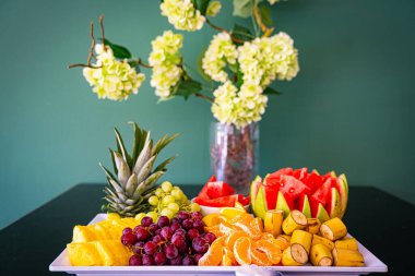Tropik meyve şarküteri tahtası, beyaz tabak, arka planda hafif fayanslar. Vejetaryen gıda konsepti