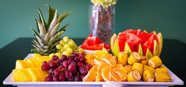 Tropik meyve şarküteri tahtası, beyaz tabak, arka planda hafif fayanslar. Vejetaryen gıda konsepti