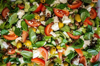 Taze domatesli sağlıklı sebze salatası, yeşil yapraklı karışım ve sebze. Koyu arkaplanda üst görünüm. Diyet menüsü