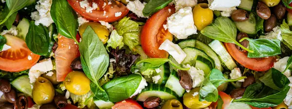 Taze domatesli sağlıklı sebze salatası, yeşil yapraklı karışım ve sebze. Koyu arkaplanda üst görünüm. Diyet menüsü