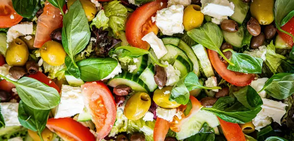 Taze domatesli sağlıklı sebze salatası, yeşil yapraklı karışım ve sebze. Koyu arkaplanda üst görünüm. Diyet menüsü