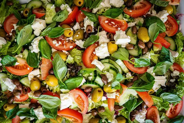 Taze domatesli sağlıklı sebze salatası, yeşil yapraklı karışım ve sebze. Koyu arkaplanda üst görünüm. Diyet menüsü