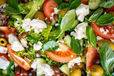 Taze domatesli sağlıklı sebze salatası, yeşil yapraklı karışım ve sebze. Koyu arkaplanda üst görünüm. Diyet menüsü