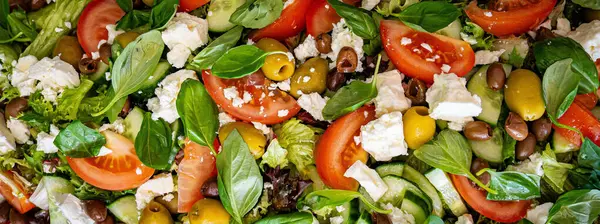 Taze domatesli sağlıklı sebze salatası, yeşil yapraklı karışım ve sebze. Koyu arkaplanda üst görünüm. Diyet menüsü