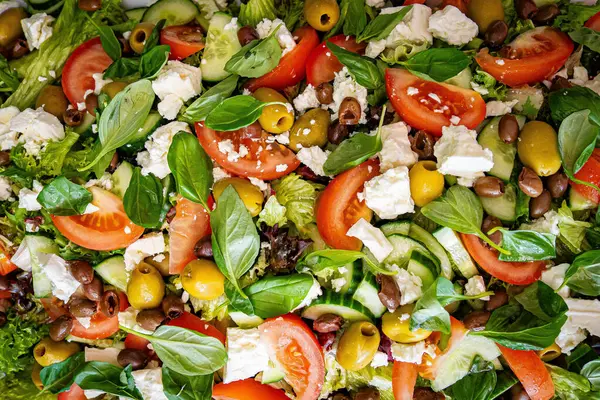 Taze domatesli sağlıklı sebze salatası, yeşil yapraklı karışım ve sebze. Koyu arkaplanda üst görünüm. Diyet menüsü