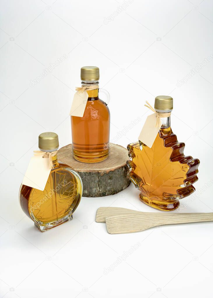 Bottles of maple syrup with blank gift tags. Delicious. Maple syrup production. Maple taffy wood