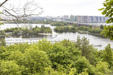 Köprü ve yemyeşil ağaçlarla panoramik şehir nehir manzarası