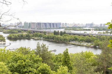 Nehir kenarındaki panoramik köprü ve yemyeşil parkla gökyüzü