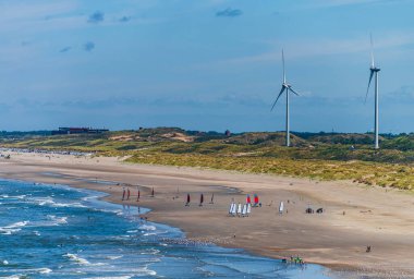 Hollanda sahillerindeki kumsallar, sahil şeridinde dinlenme gemileri ve rüzgar türbinleri var.