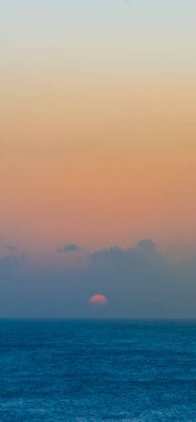 Turuncu güneş Barbados 'ta mavi okyanusun üzerinde batıyor.