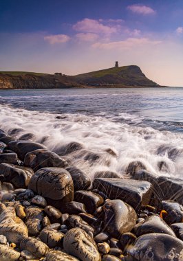 Dorset kıyısındaki Kimmeridge 'de altın saat kayaları ve denizi seyrediyor.