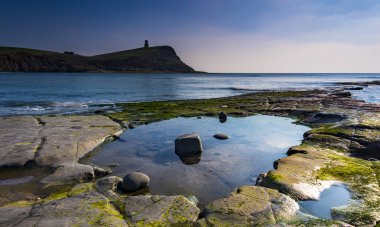 Dorset kıyısındaki Kimmeridge 'de altın saat kayaları ve denizi seyrediyor.