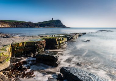 Dorset kıyısındaki Kimmeridge 'de altın saat kayaları ve denizi seyrediyor.