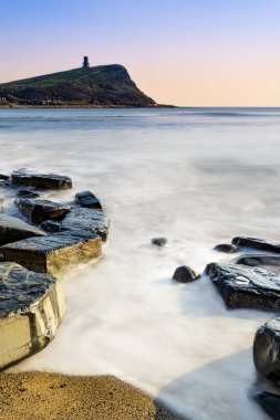Dorset kıyısındaki Kimmeridge 'de altın saat kayaları ve denizi seyrediyor.