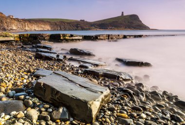 Dorset kıyısındaki Kimmeridge 'de altın saat kayaları ve denizi seyrediyor.