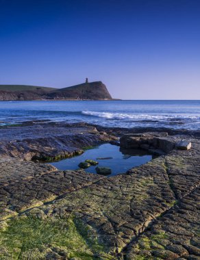 Dorset kıyısındaki Kimmeridge 'de altın saat kayaları ve denizi seyrediyor.