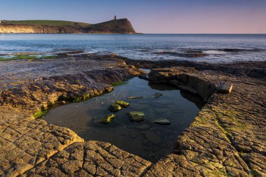 Dorset kıyısındaki Kimmeridge 'de altın saat kayaları ve denizi seyrediyor.