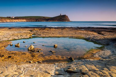 Dorset kıyısındaki Kimmeridge 'de altın saat kayaları ve denizi seyrediyor.