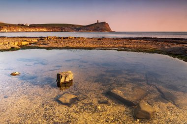 Dorset kıyısındaki Kimmeridge 'de altın saat kayaları ve denizi seyrediyor.