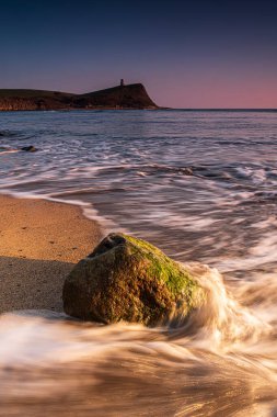 Dorset kıyısındaki Kimmeridge 'de altın saat kayaları ve denizi seyrediyor.