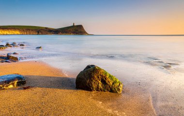 Dorset kıyısındaki Kimmeridge 'de altın saat kayaları ve denizi seyrediyor.