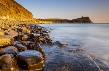 Dorset kıyısındaki Kimmeridge 'de altın saat kayaları ve denizi seyrediyor.