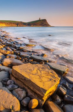 Dorset kıyısındaki Kimmeridge 'de altın saat kayaları ve denizi seyrediyor.