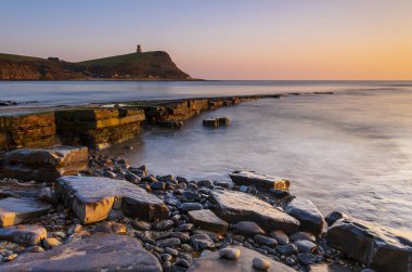 Dorset kıyısındaki Kimmeridge 'de altın saat kayaları ve denizi seyrediyor.