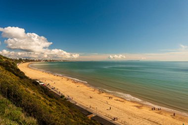 Bournemouth sahilindeki sakin sular gün batımında batan güneş tarafından aydınlatılıyor.