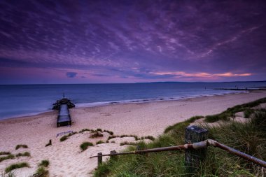 Southbourne sahilindeki sakin sular gün batımında batan güneş tarafından aydınlatılıyor.