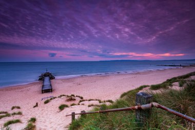 Southbourne sahilindeki sakin sular gün batımında batan güneş tarafından aydınlatılıyor.
