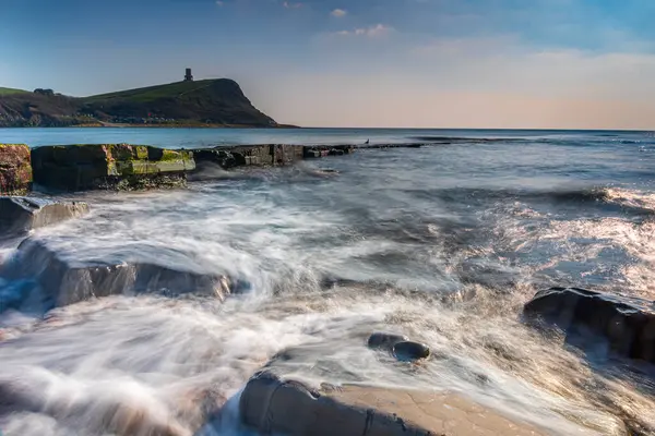 Dorset kıyısındaki Kimmeridge 'de altın saat kayaları ve denizi seyrediyor.
