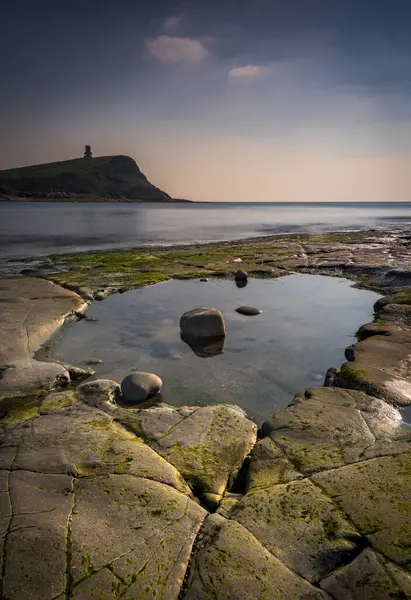 Dorset kıyısındaki Kimmeridge 'de altın saat kayaları ve denizi seyrediyor.