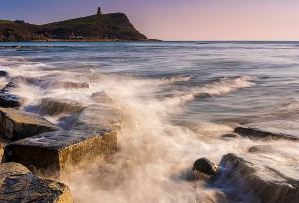 Dorset kıyısındaki Kimmeridge 'de altın saat kayaları ve denizi seyrediyor.
