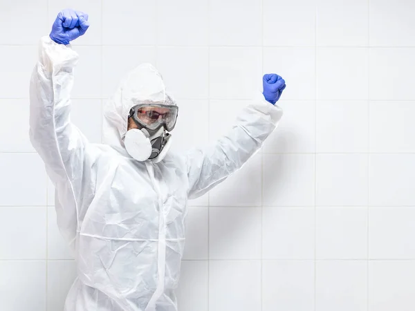 scientist with protective equipment with their arms up