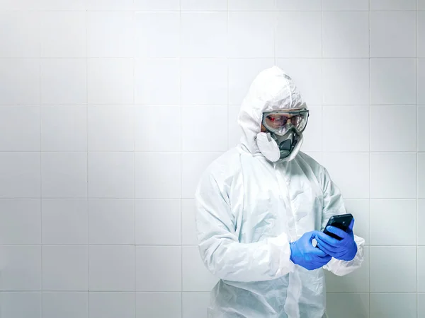Scientist with protective equipment using smartphone