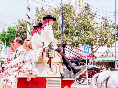 Seville, Spain - May 04, 2022 : Men in traditional costume on a horse-drawn carriage at the April Fair, Feria de Sevilla, Andalusia, Spain.