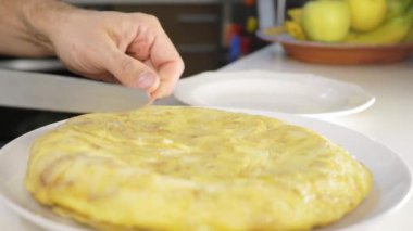 İspanyol omleti kesip tabakta servis eden bir adam. Seçici odak.