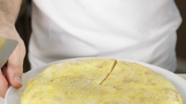 Man serving a Spanish omelet on a plate. Selective focus.