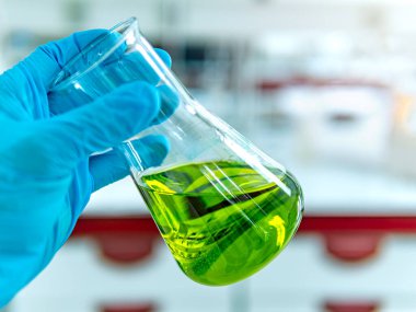 Laboratuvar kabı plastik eldiven analist'ın elinde.