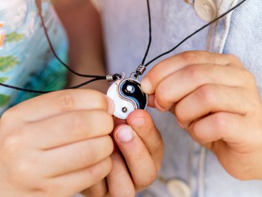 Yin Yang kolyesini birbirine bağlayan çocuk elleri..