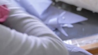Yaşlı bir kadının iğne ve iplikle elle dikildiği yakın plan. Seçici odak.