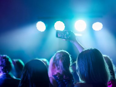 Genç bir kadın cep telefonuyla konser kaydı yapıyor. Gece hayatı ve disko konsepti. Seçici Odaklanma