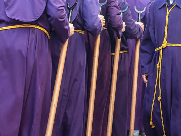 Mor cüppeli ve sarı kemerli insanlar tören sırasında tahta sopa tutuyorlar. Seçici Odaklanma.